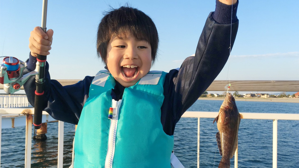 5-8歳の子どもが自分で釣り竿を持って本格的な釣りを楽しんでいる様子、釣った魚と記念撮影